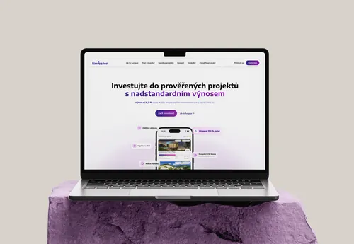 Notebook s homepage webu Finvestor na fialovém podstavci