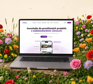 Notebook s webem Finvestor stojící mezi lučními květinami